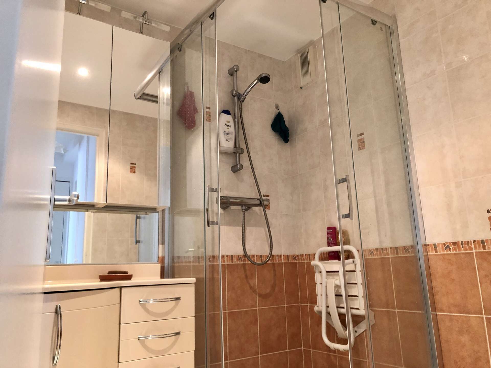 Een moderne badkamer met een douche met glazen wand, een wastafel met spiegel en een handdoekrek.
