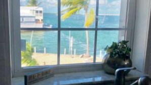 A kitchen with a large window overlooking a beach and ocean. - Venture Out Million Dollar Ocean View (Cudjoe Key)