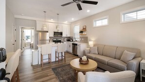 Une cuisine moderne avec des armoires blanches, un îlot central et un ventilateur de plafond.