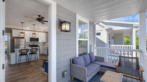 A covered porch with a seating area, a kitchen with modern appliances, and a ceiling fan.