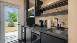 Une cuisine moderne dotée d’un plan de travail noir, d’appareils électroménagers en acier inoxydable et offrant une vue sur l’extérieur.