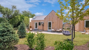 Un bâtiment en bois doté d’un patio, d’un espace extérieur aménagé avec des sièges et d’un fauteuil suspendu.