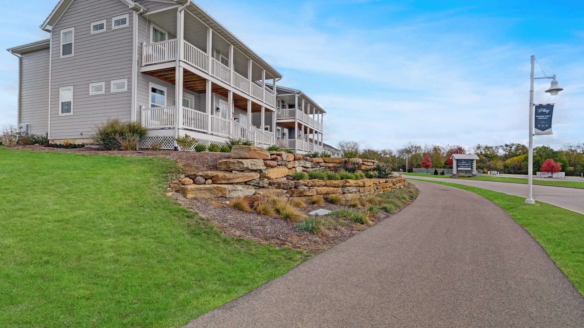 A two-story building with a porch, a stone retaining wall, and a paved walkway.