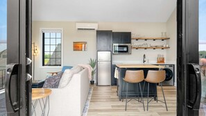 A modern kitchen with a refrigerator, microwave, and sink. There is a dining area with a table and chairs.