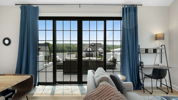 En moderne stue med en stor skydedør, der fører ud til en balkon med udendørs møbler.