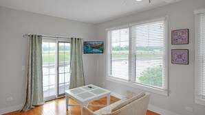 A room with a sliding glass door, a flat-screen TV, a small table, a sofa, and two framed pictures on the wall. - 2 Great Loop West - River Resort Cottage Community in Starved Rock Country (Ottawa)