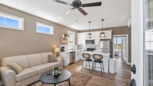 A modern kitchen with white cabinets, a central island, and a ceiling fan. - Dog Friendly Condo | Navvy Town Neighborhood (Ottawa)