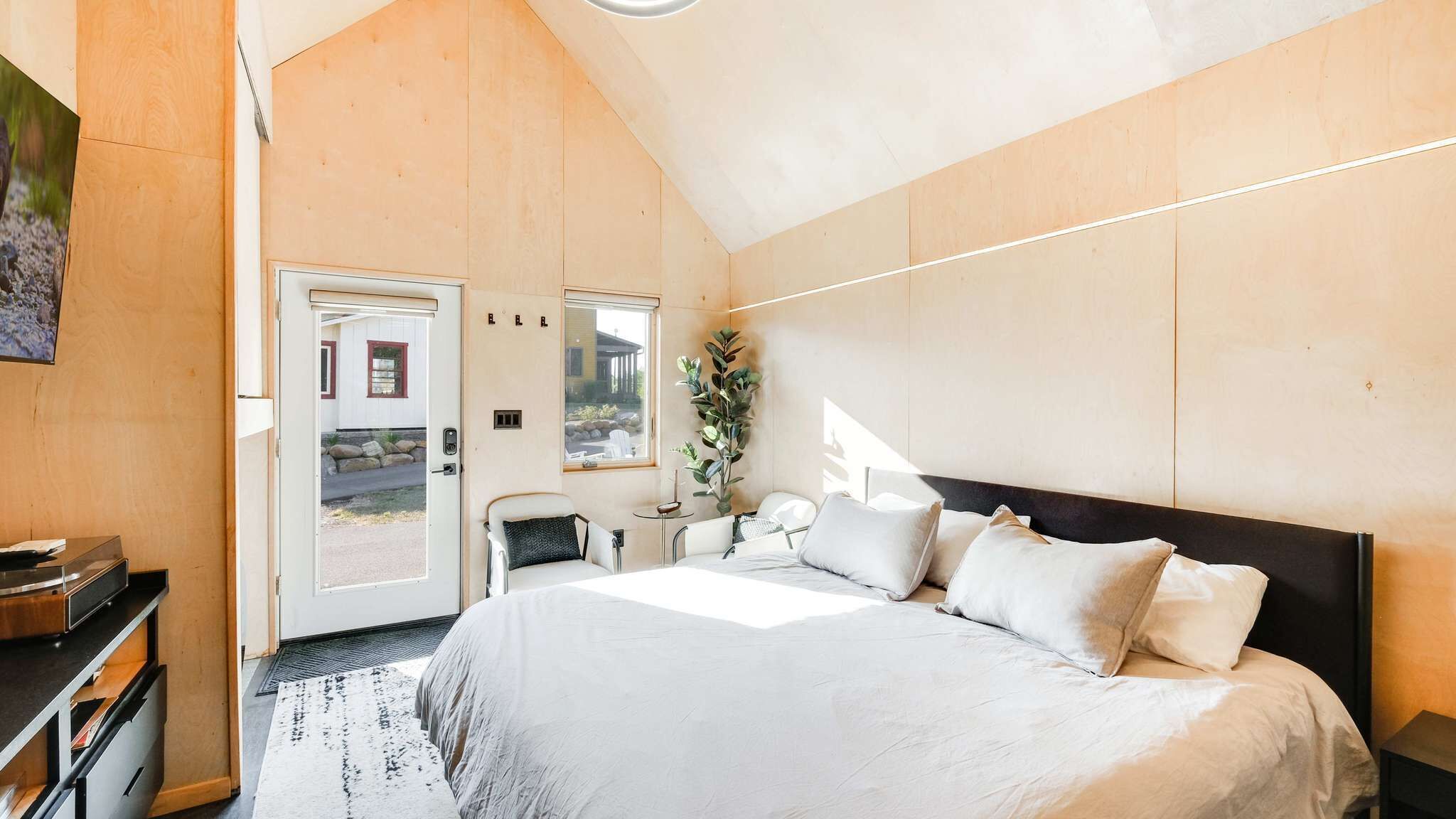 A bedroom with a bed, bedside table, and a view of the outside.