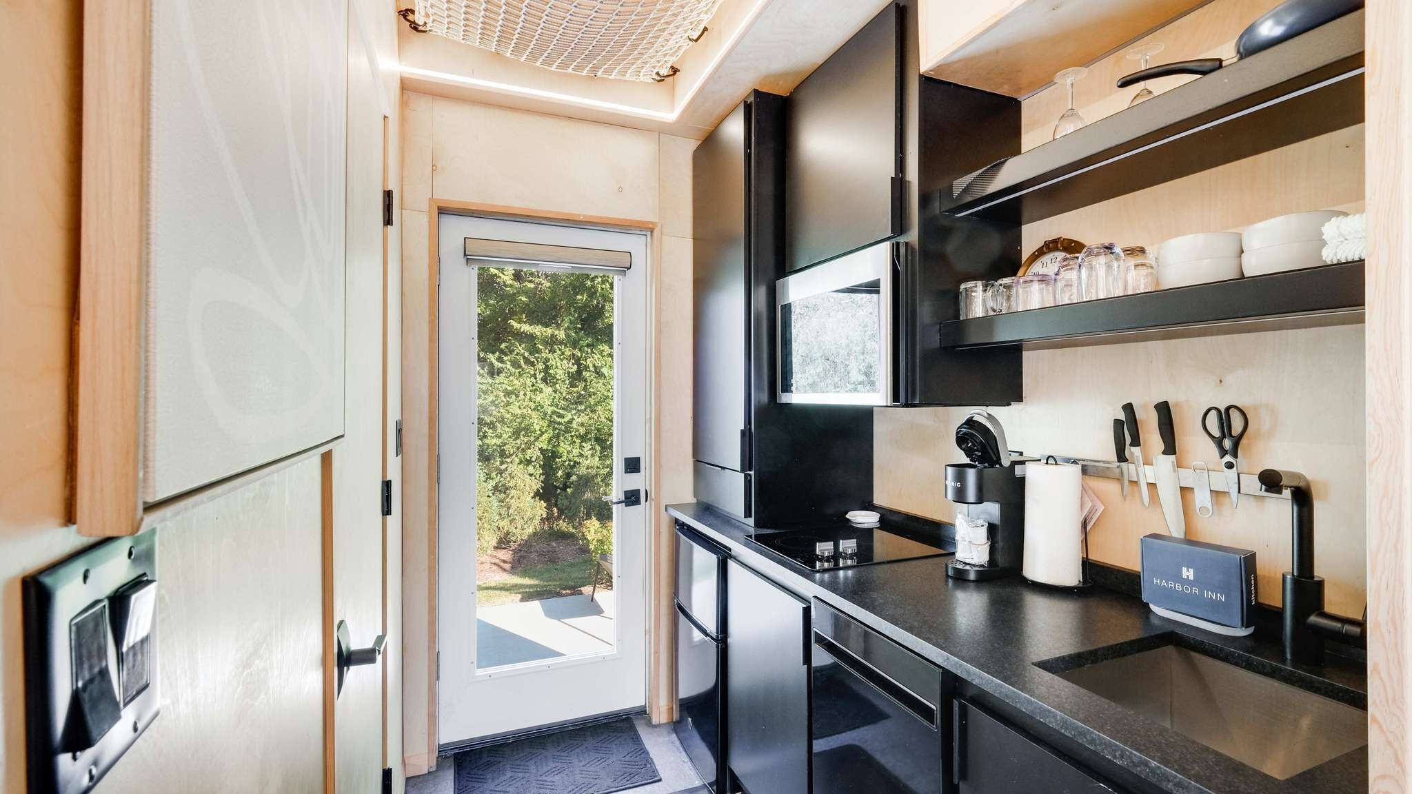 A compact kitchen with a coffee machine, knife set, and a small refrigerator.