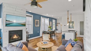A living room with a fireplace, a dining area, and a kitchen with a gas stove.