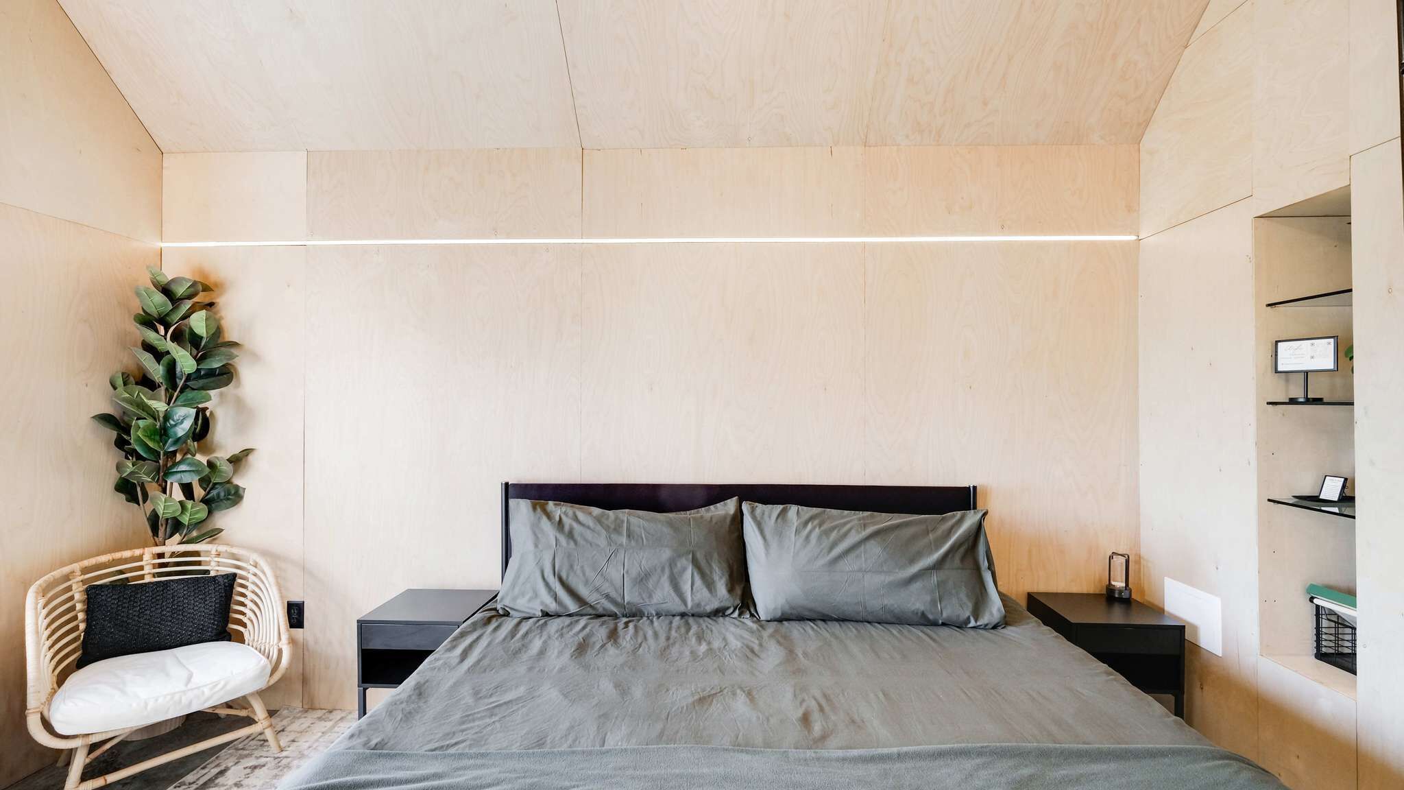 Une chambre à coucher moderne, avec un lit, des tables de chevet, une chaise et une étagère fixée au mur.