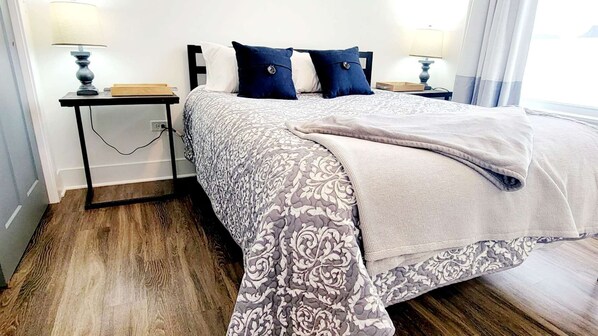 A hotel room with a bed, two bedside tables, a lamp on each table, and a window with curtains.