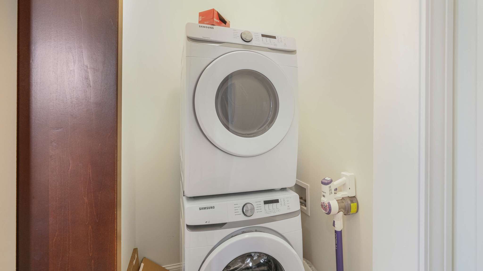 Un appareil combiné lave-linge et sèche-linge, de type « empilable », doté d’un panneau de commande, d’une prise de courant et d’un tuyau.