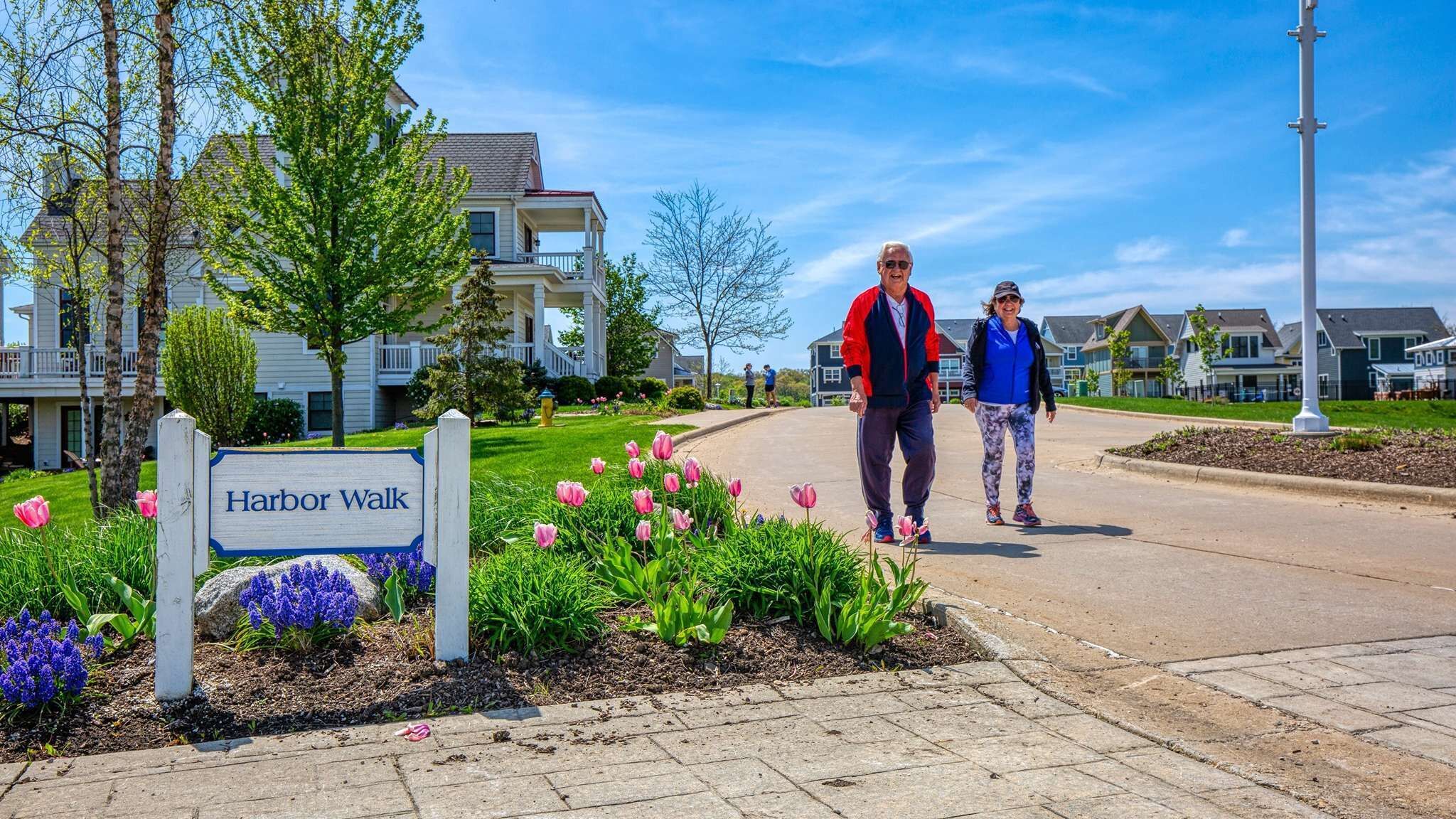 Une rue résidentielle avec un panneau indiquant « Harbor Walk », des maisons et un chemin piétonnier.