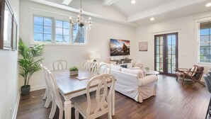 A dining area with a wooden table and chairs, a chandelier, and a television.