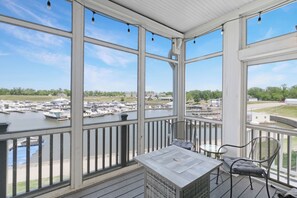 A covered outdoor area with a view of a marina, featuring a table and chairs.