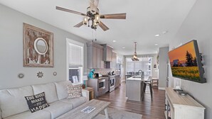 A modern living room with a sofa, coffee table, and a ceiling fan. - Striking Waterfront Villa Home (Ottawa)