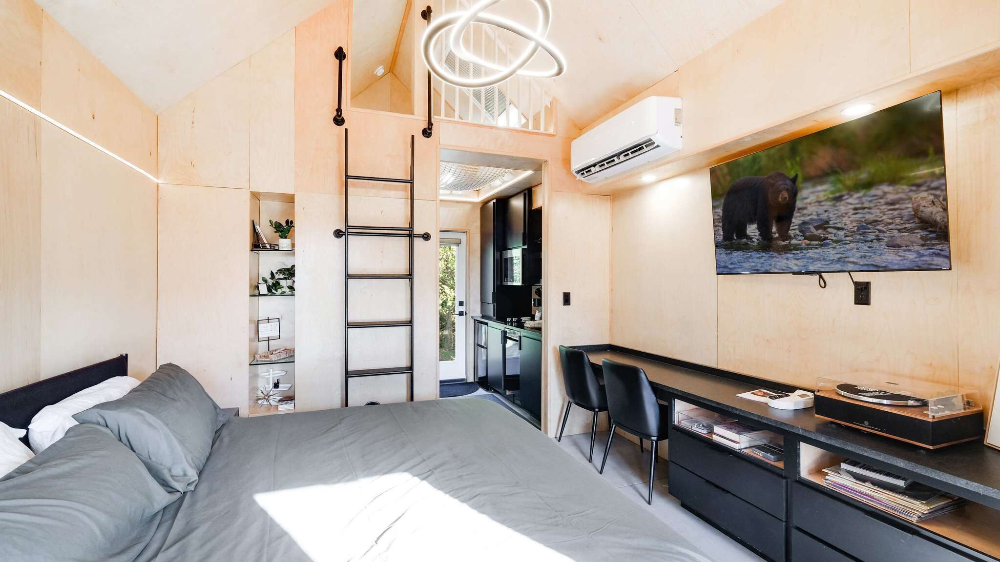 Une chambre à coucher avec un lit, un bureau, une chaise, une télévision et une échelle.