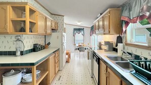 Uma cozinha compacta com armários de madeira, pia e área de refeições com mesa e cadeiras.