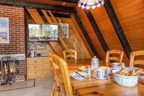 Un rincón comedor acogedor con muebles de madera, chimenea y un televisor que muestra una vista panorámica.