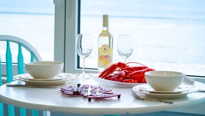 A table set with white bowls, a bottle of liquor, and a plate of red lobsters.