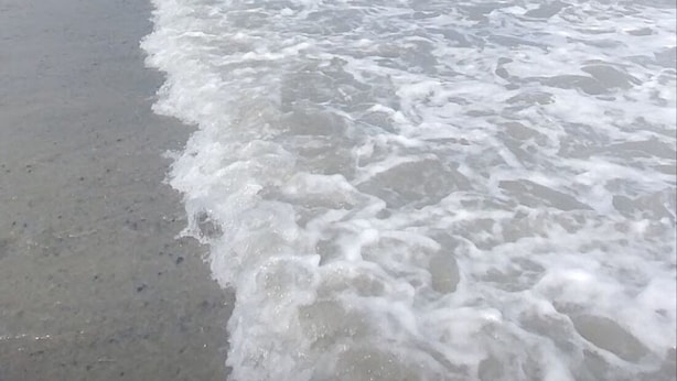 A beach with gentle waves and a clear sky.