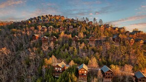 A cluster of log cabins in a forested area with multiple levels and balconies.