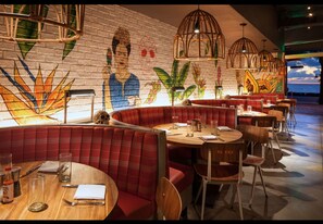 Enjoy meals in a vibrant dining area with a unique mural and comfortable booths.