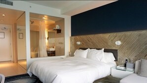 A modern bedroom with a large bed, a bedside table, a nightstand, and a mirror.