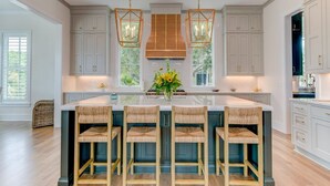 A spacious kitchen with a central island, bar stools, pendant lighting, and a view of the outdoors. - Brand New Luxury 6 bedrooms, 7.5 bathrooms, pool, spa, elevator, ocean views (Isle Of Palms)