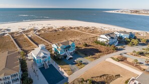 A coastal residential area with beachfront properties, including a large house with a balcony and a smaller house with a swimming pool.