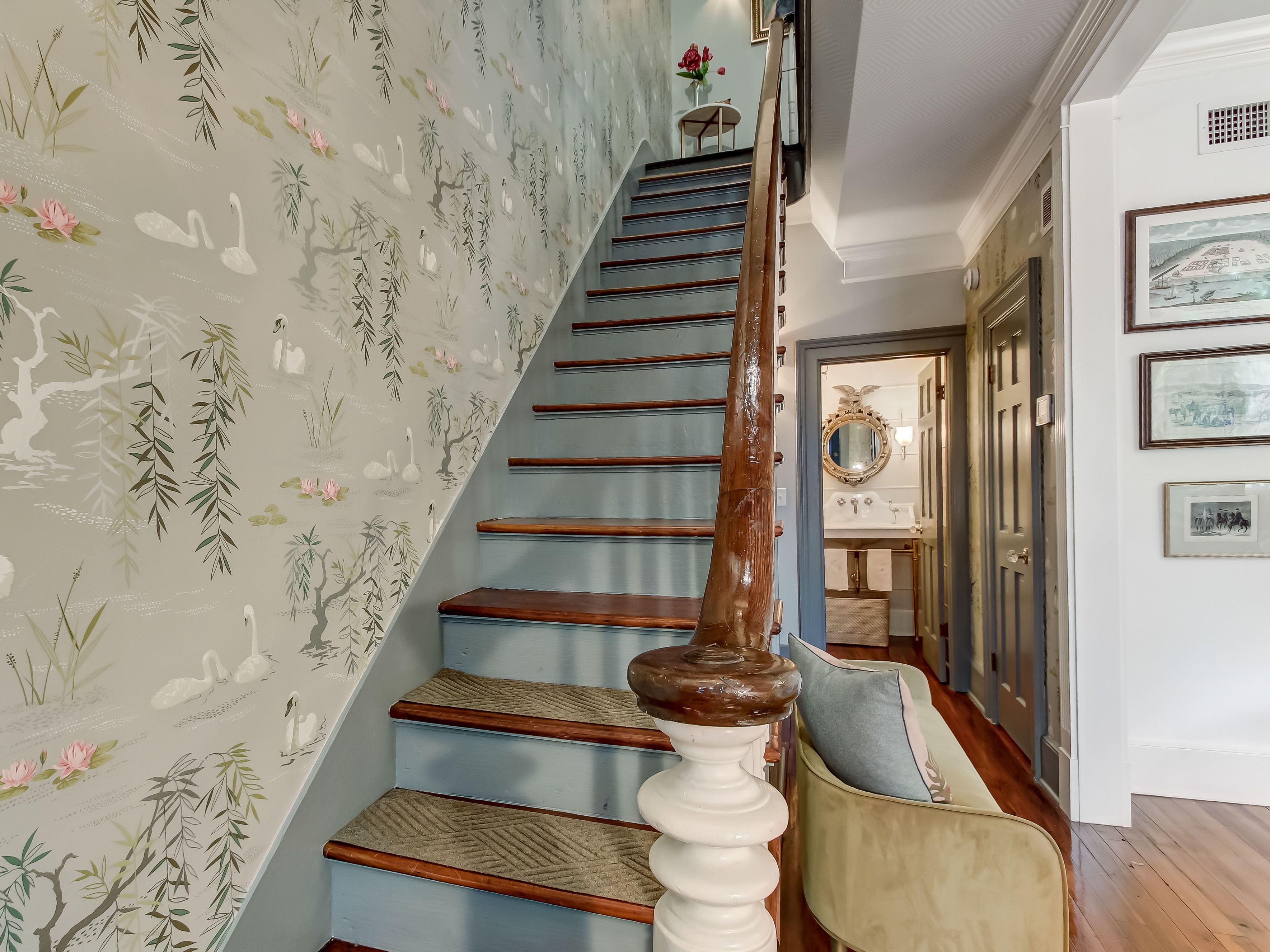 A staircase with a wooden handrail and a floral wallpaper design.