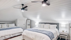 A bedroom with two beds, a ceiling fan, and a nightstand with a lamp.