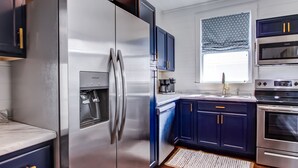 A modern kitchen with stainless steel appliances, dark blue cabinets, and a built-in water dispenser.