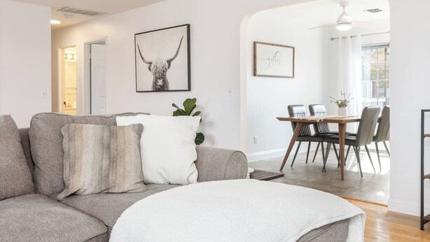 A modern living room with a gray sofa, a dining area with a wooden table and chairs, and a hallway leading to another room. - Mulberry Dreams+Stocked Kitchen+Backyard+Wineries (Templeton)