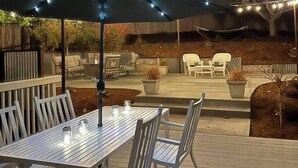 An outdoor patio area with a table and chairs, string lights, and a covered seating area. - Mulberry Dreams+Stocked Kitchen+Backyard+Wineries (Templeton)