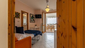 A bedroom with a bed, a desk, a chair, a television, and a balcony.