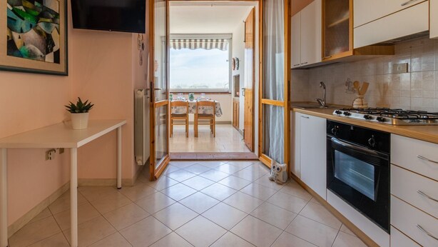 A kitchen with a stove, oven, and a dining area with chairs and a table.