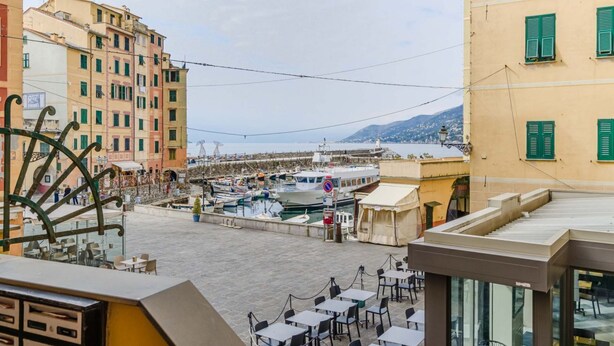 Vistes al front marítim amb edificis, un moll i embarcacions, i zones d'aixopluc a l'aire lliure.