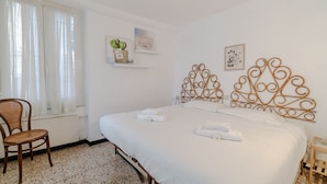 Habitació d'hotel amb llit, una cadira, finestra amb cortines i decoració a les parets.