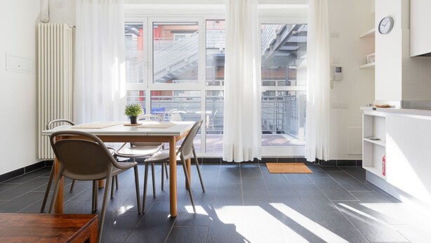 A modern kitchen with white cabinets, a clock, and a view through the window. - GuestHost - Industrial Design Apt near M4 Tolstoy (Milano)