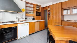 Eine moderne Küche mit Holzausbau, Backofen, Mikrowelle und einem Essbereich mit Holztisch.