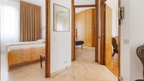 Ein Schlafzimmer mit Bett, Stuhl, Kleiderschrank und einer Tür zu einem anderen Raum.