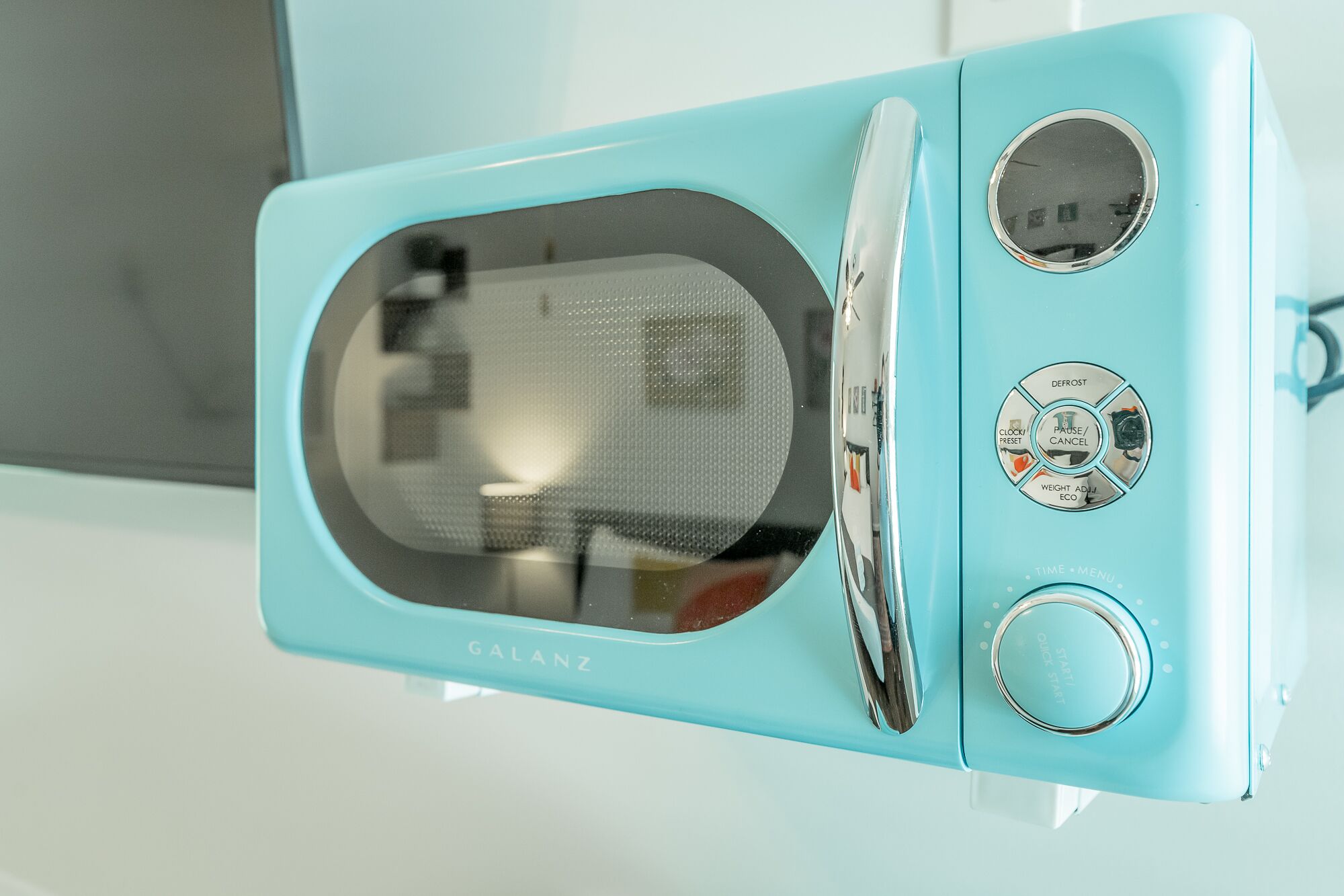 Eine türkis-farbene Mikrowelle mit digitalem Display und Bedienelementen.