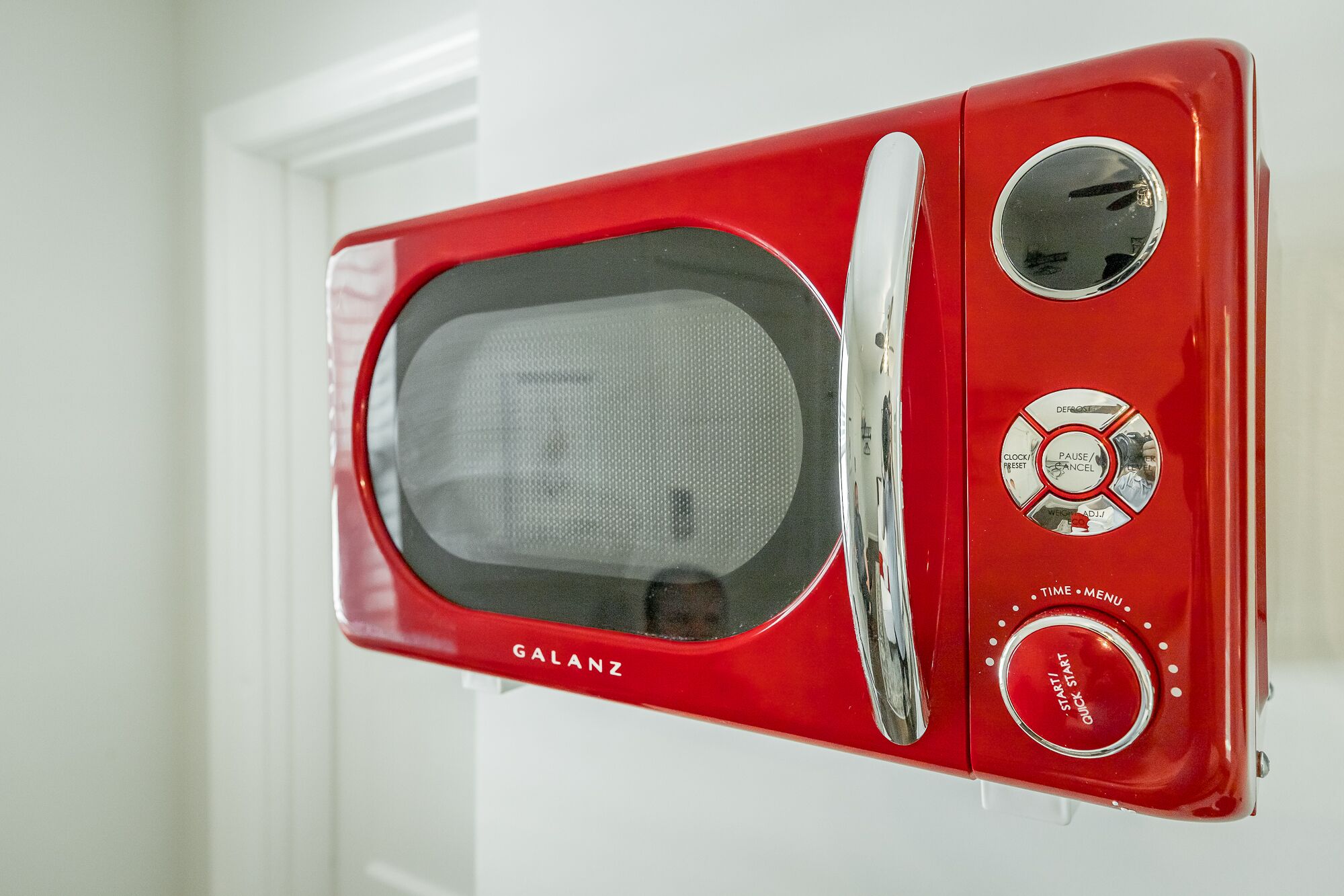 Een rode magnetron bevestigd aan een witte muur.