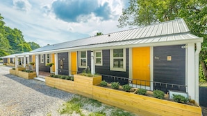 Une rangée de chalets de plain-pied, coiffés d’un toit en métal, chacun doté d’un petit porche et d’une porte jaune.