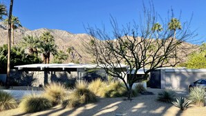 A modern house with a stone facade, a covered patio, and a desert landscape in the background. - MCM Poolside Paradise - Mountain Views & Total Privacy (Palm Springs)