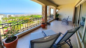 Un balcón con vista a un paisaje urbano, una planta en maceta y dos sillas.