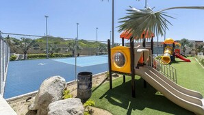 Un parque infantil con tobogán, estructura de escalada y una pequeña zona de piscina.