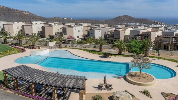 Un resort con una amplia piscina, varias villas y vista al océano.